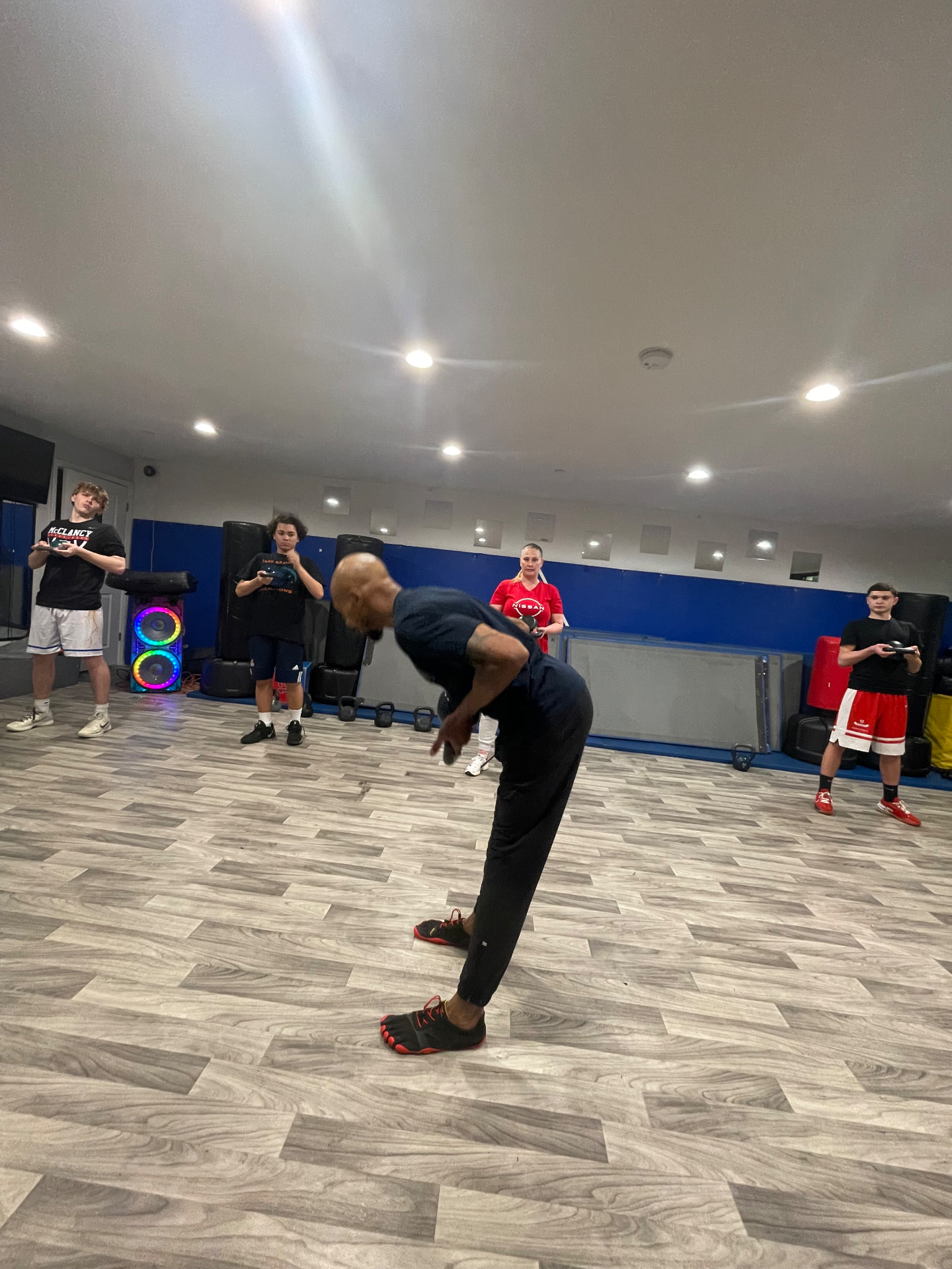 FKS coach demonstrating a kettlebell hinge with students in a Queens training class