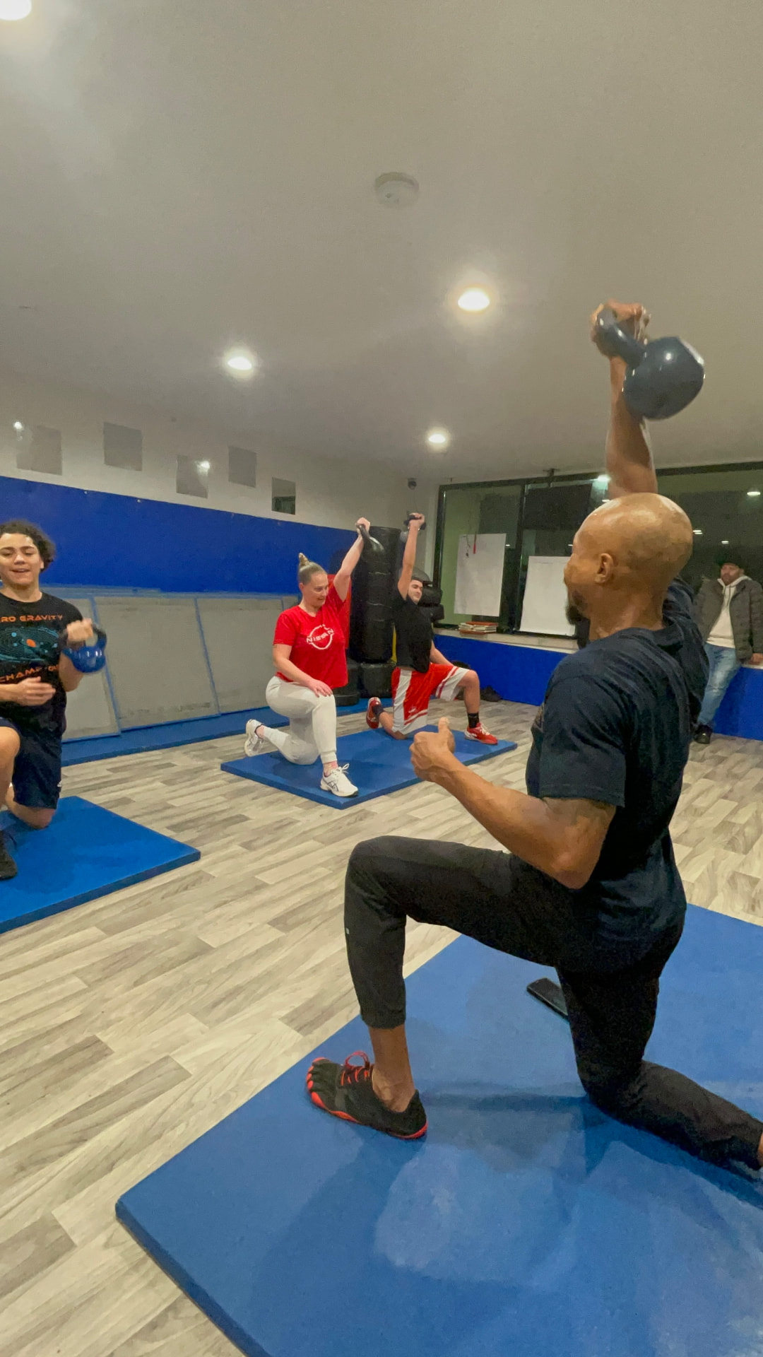 Half-kneeling kettlebell overhead press in a group class