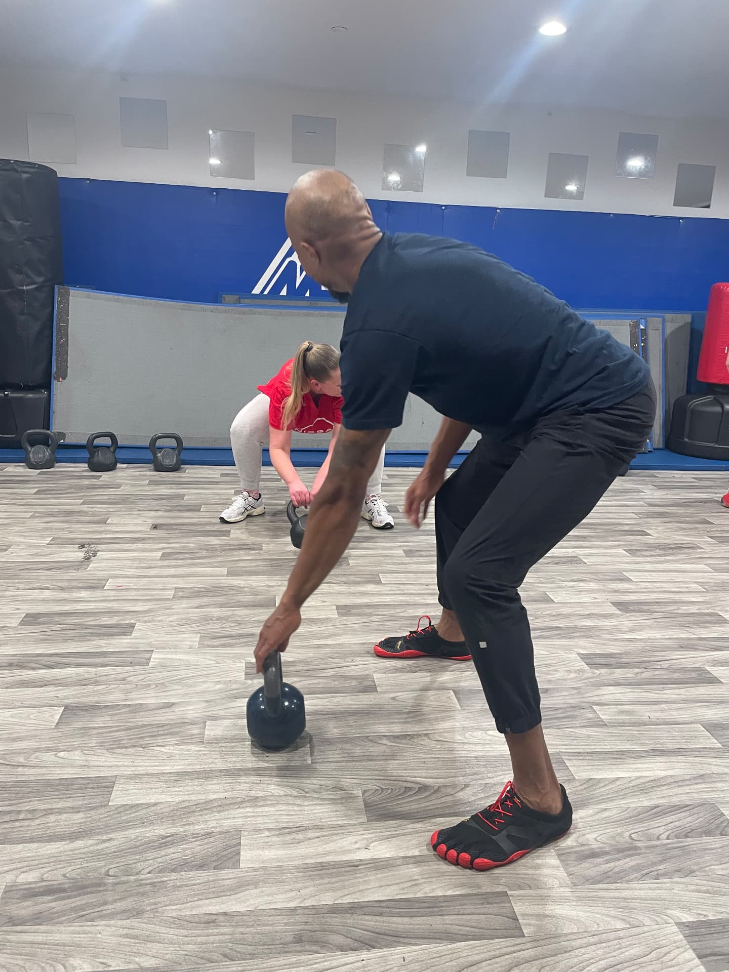 Coach demonstrating a single-arm kettlebell deadlift setup